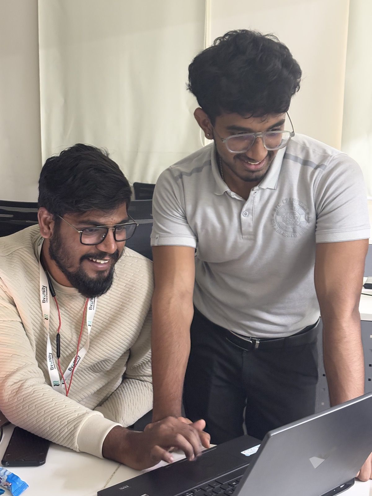 Two students laughing over a laptop