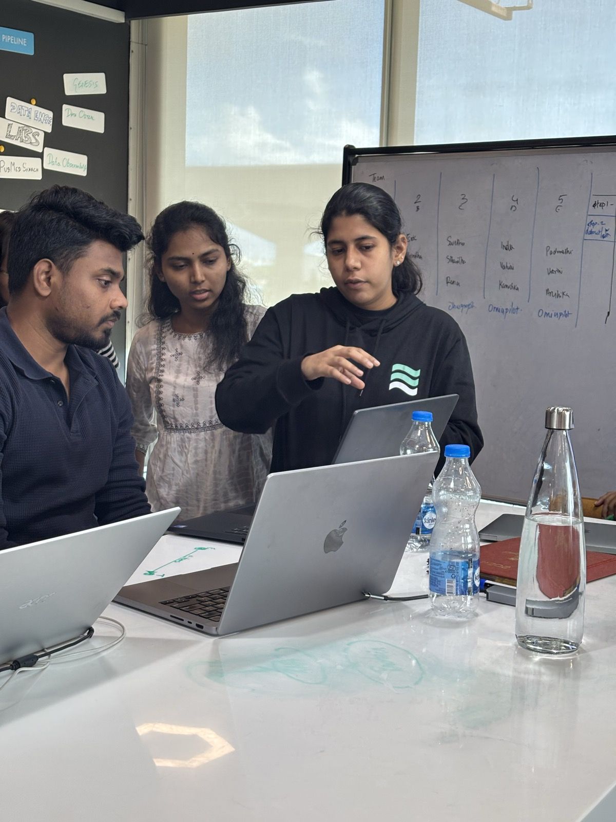 A mentor explaining code to students at their laptops
